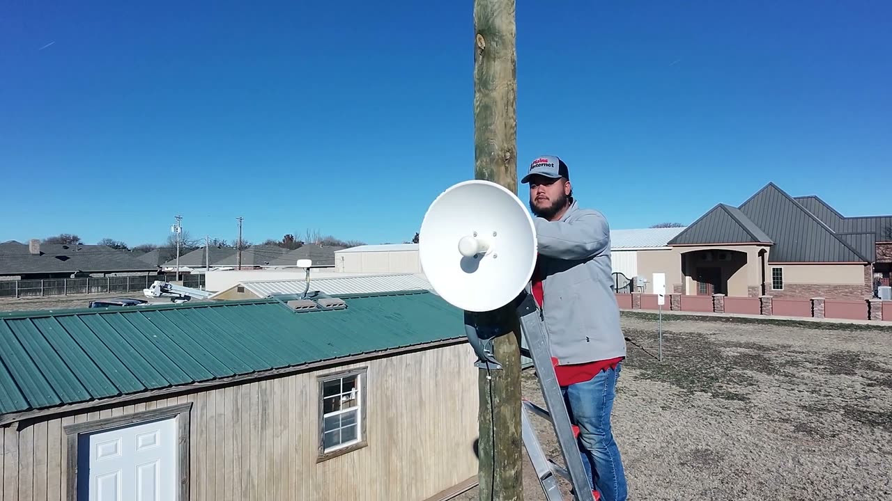 A Plains Internet technician mounting a dish on a pole